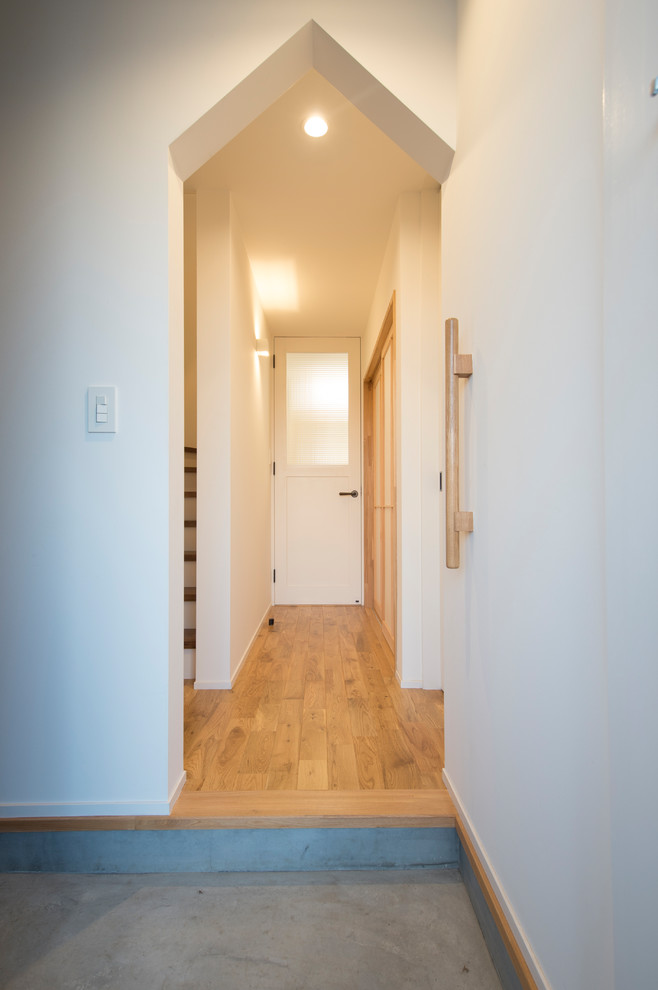 Kleiner Moderner Eingang mit Korridor, weißer Wandfarbe, Betonboden, Einzeltür, weißer Haustür und grauem Boden in Sonstige