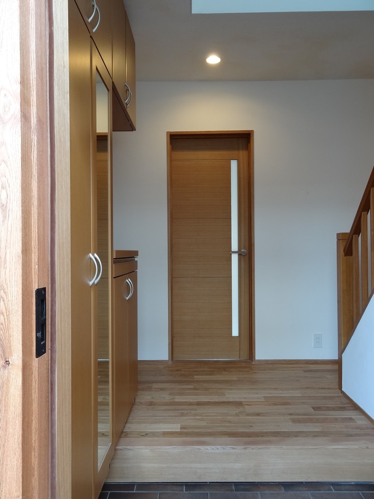 Esempio di un grande corridoio scandinavo con pareti bianche, pavimento in mattoni, una porta singola, una porta in legno bruno e pavimento marrone
