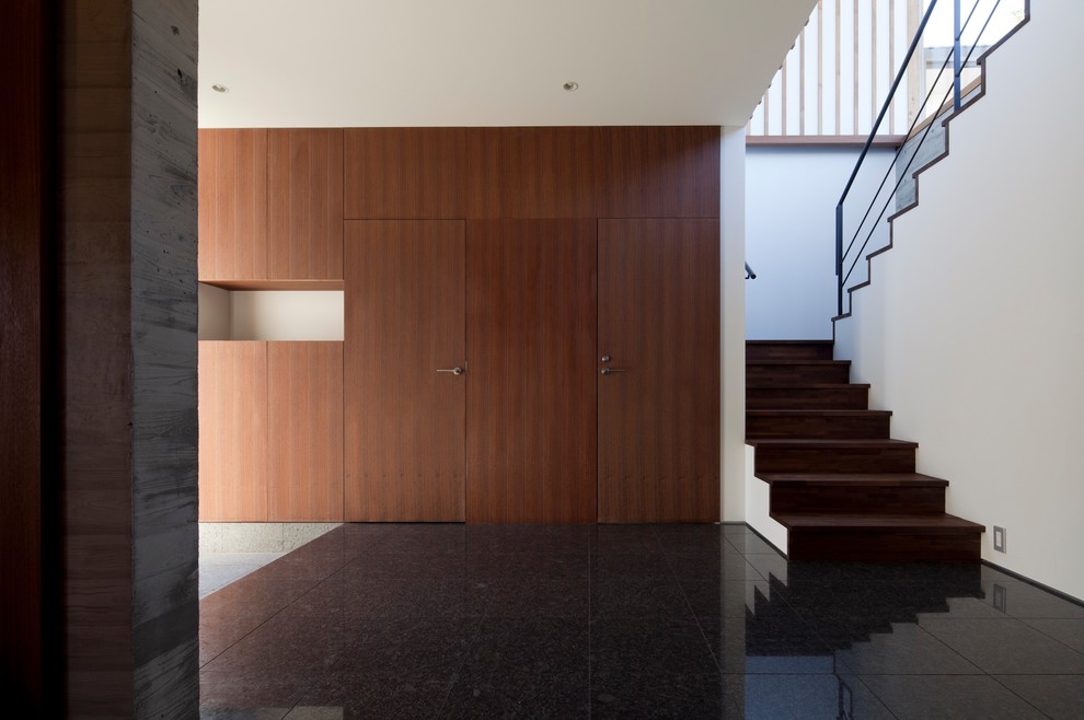Foto di un grande ingresso minimalista con pareti marroni, pavimento in granito, una porta singola, una porta marrone e pavimento grigio