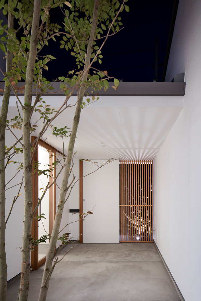 Foto de puerta principal de estilo zen con paredes blancas, suelo de cemento, puerta simple, puerta de vidrio y suelo gris