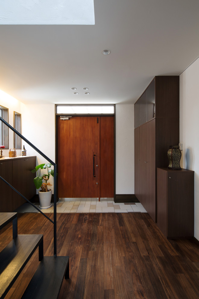 他の地域にあるアジアンスタイルのおしゃれな玄関 (白い壁、濃色無垢フローリング、木目調のドア、茶色い床) の写真