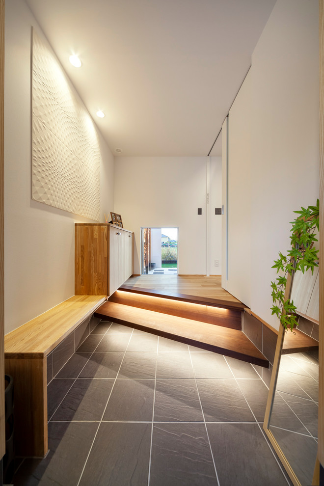Ejemplo de hall de estilo zen con paredes blancas, puerta negra y suelo gris