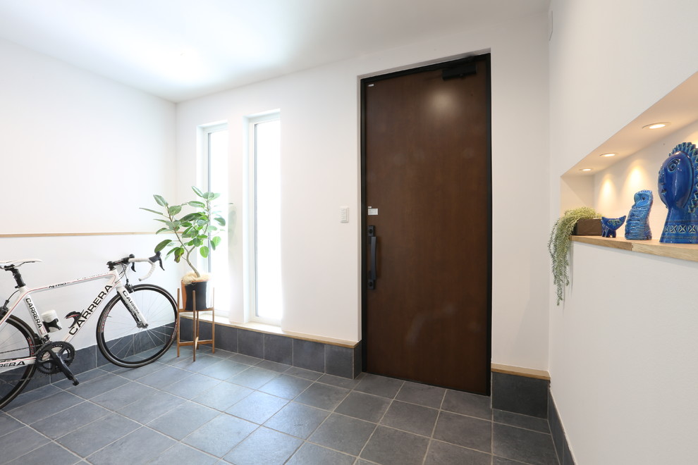 Cette photo montre une entrée moderne avec un couloir, un mur blanc, une porte simple, une porte marron et un sol vert.