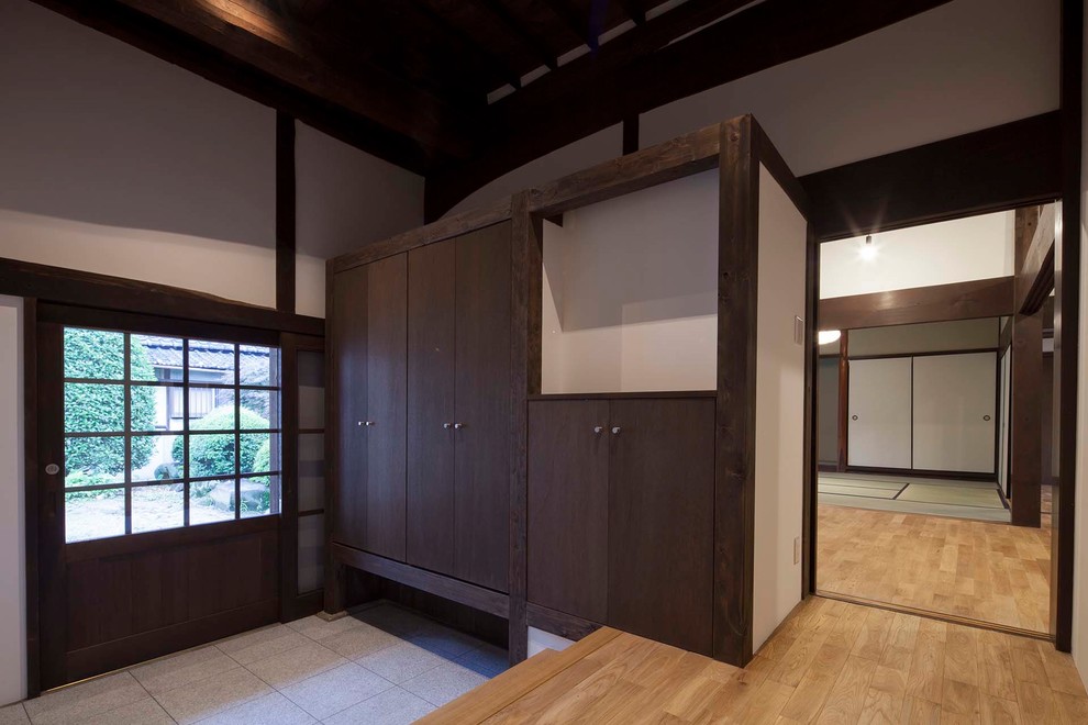 Imagen de hall de estilo zen grande con paredes blancas, suelo de granito, puerta corredera, puerta de madera oscura y suelo gris