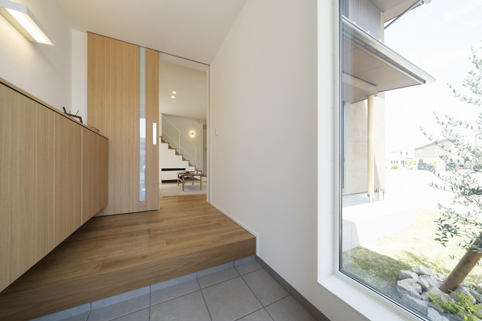 Imagen de hall minimalista con paredes blancas, suelo de contrachapado, puerta simple, puerta negra, suelo marrón, papel pintado y papel pintado