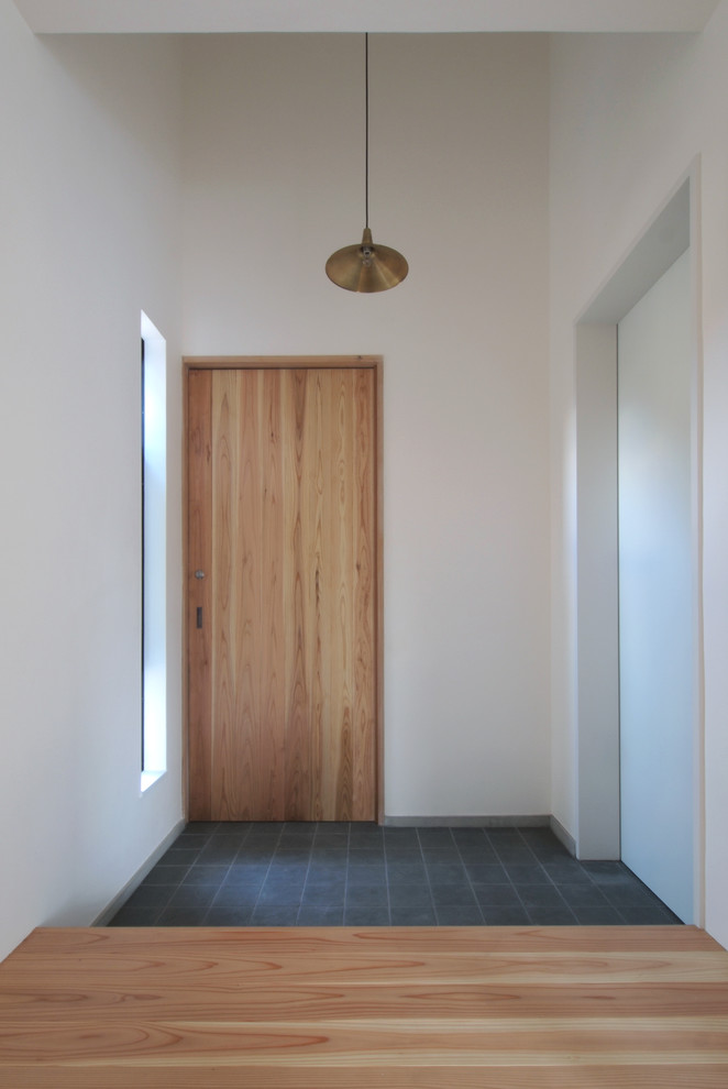 Foto di un corridoio etnico di medie dimensioni con pareti bianche, pavimento in legno massello medio, una porta scorrevole, una porta in legno bruno e pavimento marrone