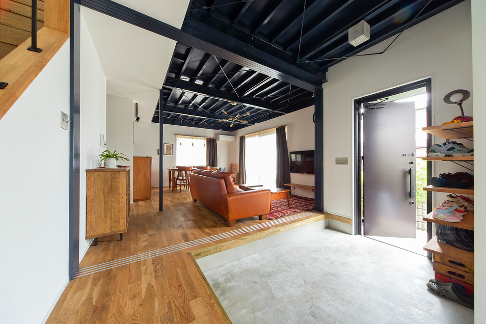 Источник вдохновения для домашнего уюта: узкая прихожая среднего размера в стиле лофт с белыми стенами, бетонным полом, одностворчатой входной дверью и черной входной дверью