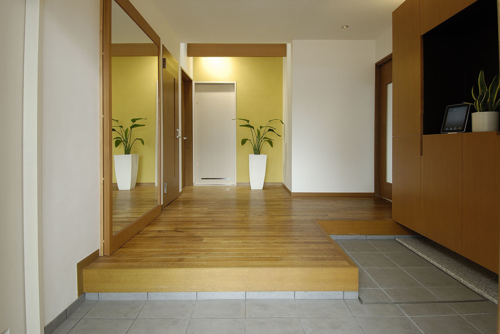 На фото: узкая прихожая в скандинавском стиле с желтыми стенами, паркетным полом среднего тона, коричневым полом и входной дверью из дерева среднего тона с