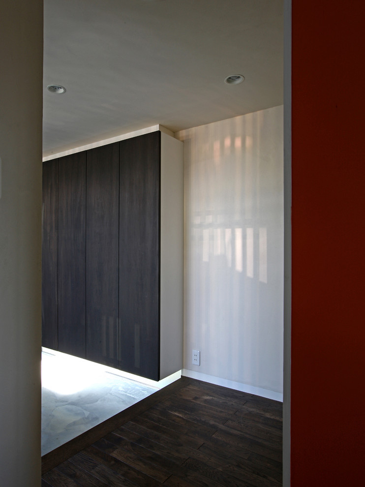 Imagen de entrada de estilo zen de tamaño medio con paredes rojas, suelo de cemento y puerta de vidrio
