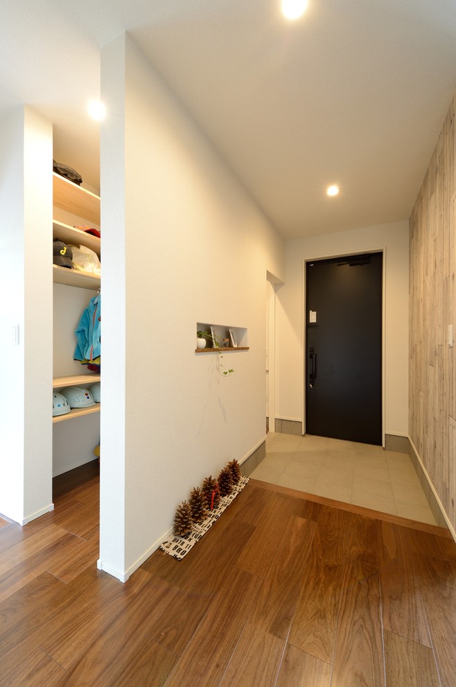 На фото: узкая прихожая в стиле рустика с разноцветными стенами, паркетным полом среднего тона, одностворчатой входной дверью, черной входной дверью и коричневым полом с