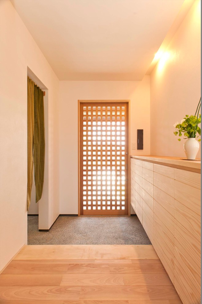 Imagen de entrada asiática con paredes blancas, puerta simple y suelo gris