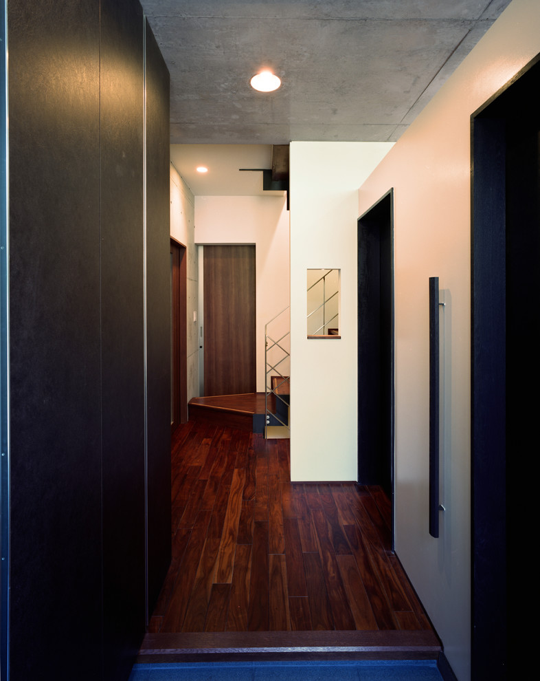Inredning av en 60 tals mellanstor hall, med bruna väggar, mörkt trägolv, en enkeldörr, en svart dörr och svart golv