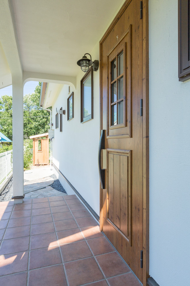 Cette image montre une porte d'entrée chalet avec un mur blanc, une porte simple et une porte en bois brun.