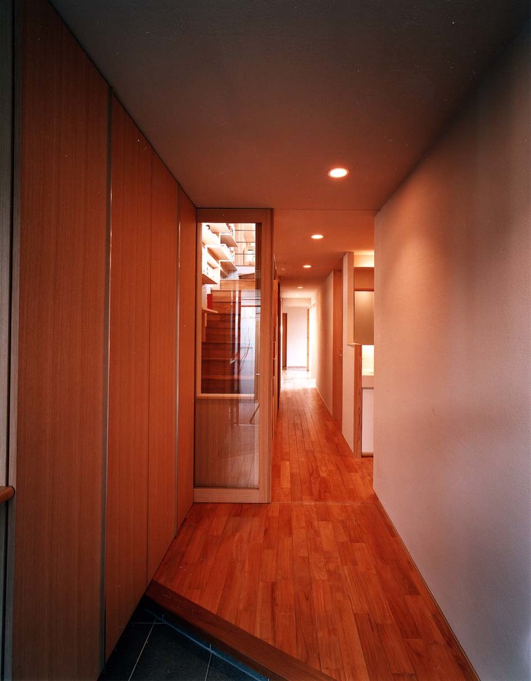 Immagine di un corridoio di medie dimensioni con pareti bianche, pavimento in gres porcellanato, una porta singola, una porta marrone e pavimento grigio