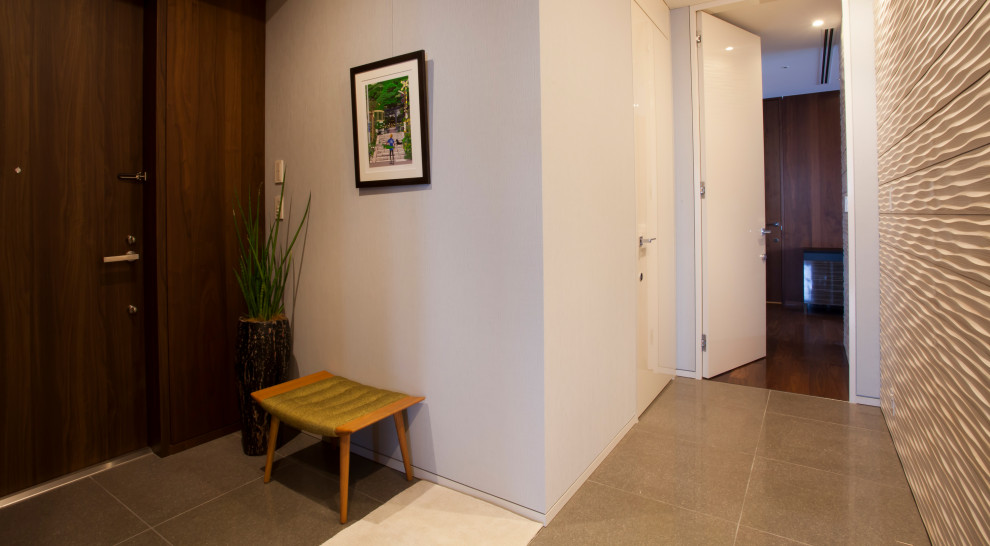 広いコンテンポラリースタイルのおしゃれな玄関 (ベージュの壁、グレーの床) の写真