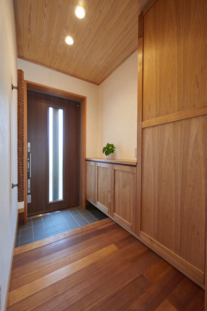 他の地域にあるアジアンスタイルのおしゃれな玄関 (白い壁、無垢フローリング、濃色木目調のドア、ベージュの床、板張り天井) の写真