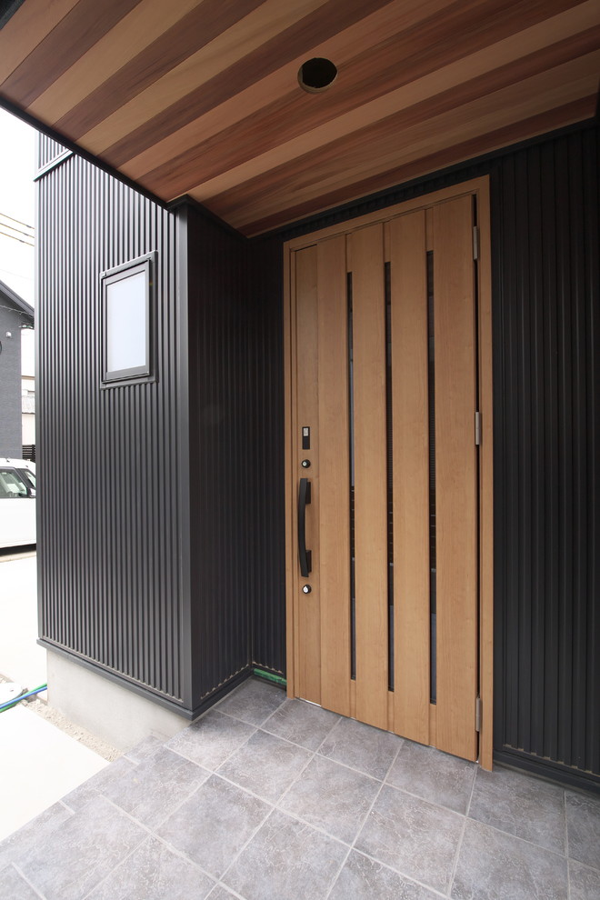 大阪にあるモダンスタイルのおしゃれな玄関ドア (黒い壁、淡色無垢フローリング、淡色木目調のドア、ベージュの床) の写真