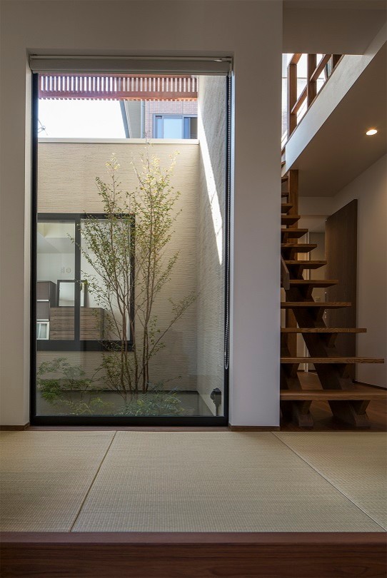 Immagine di un grande corridoio minimalista con pareti bianche, pavimento in tatami, una porta singola, una porta in legno scuro e pavimento marrone