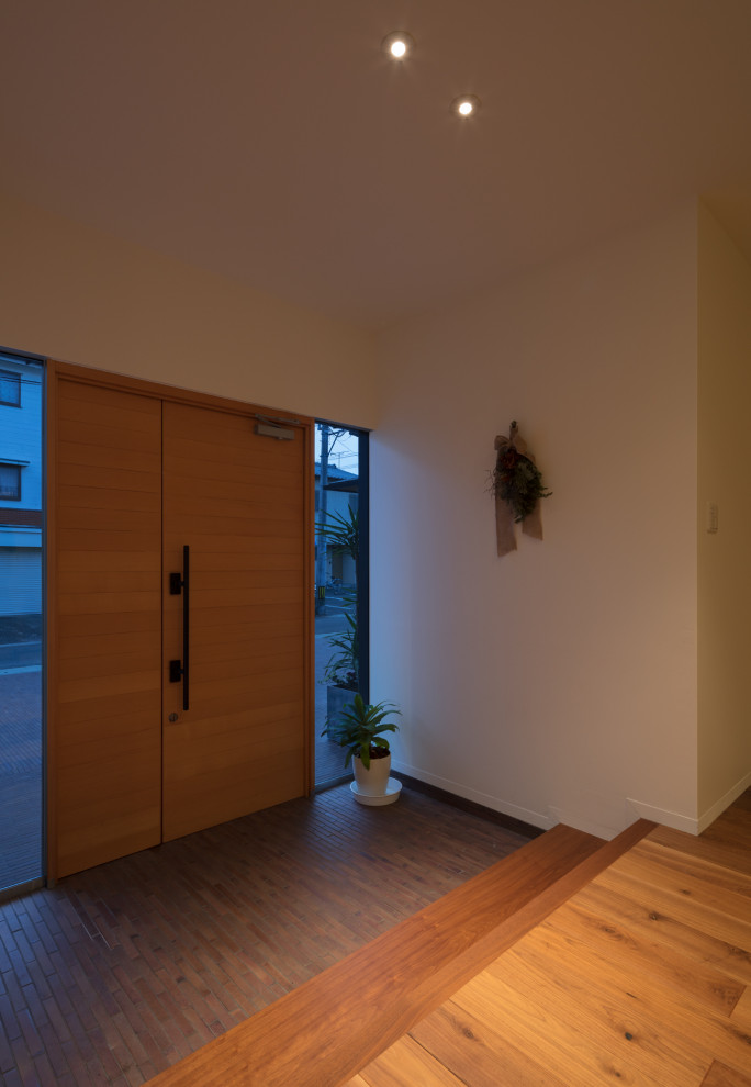 Idee per un grande ingresso moderno con pareti bianche, pavimento in compensato, una porta a due ante, una porta in legno bruno e pavimento marrone