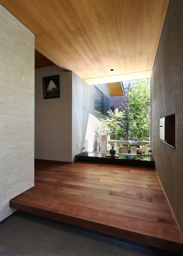 Aménagement d'une entrée moderne avec un mur beige, une porte simple, une porte marron et un sol gris.