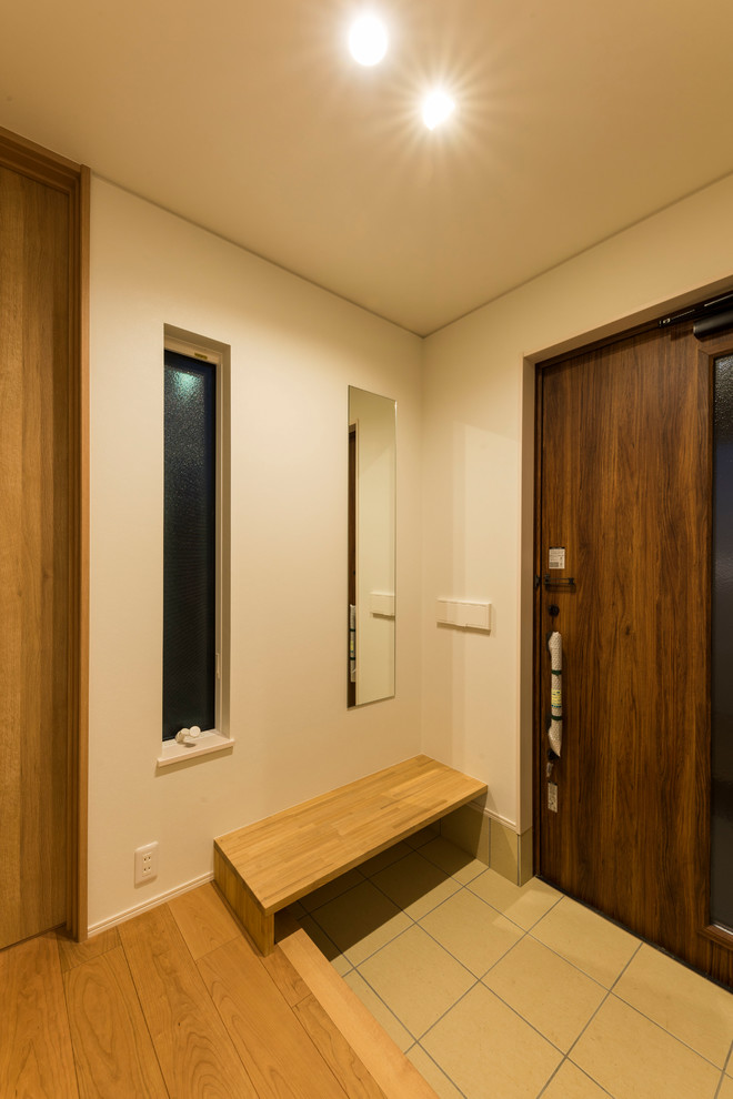 Kleiner Moderner Eingang mit Korridor, weißer Wandfarbe, Keramikboden, Einzeltür, dunkler Holzhaustür und beigem Boden in Sonstige