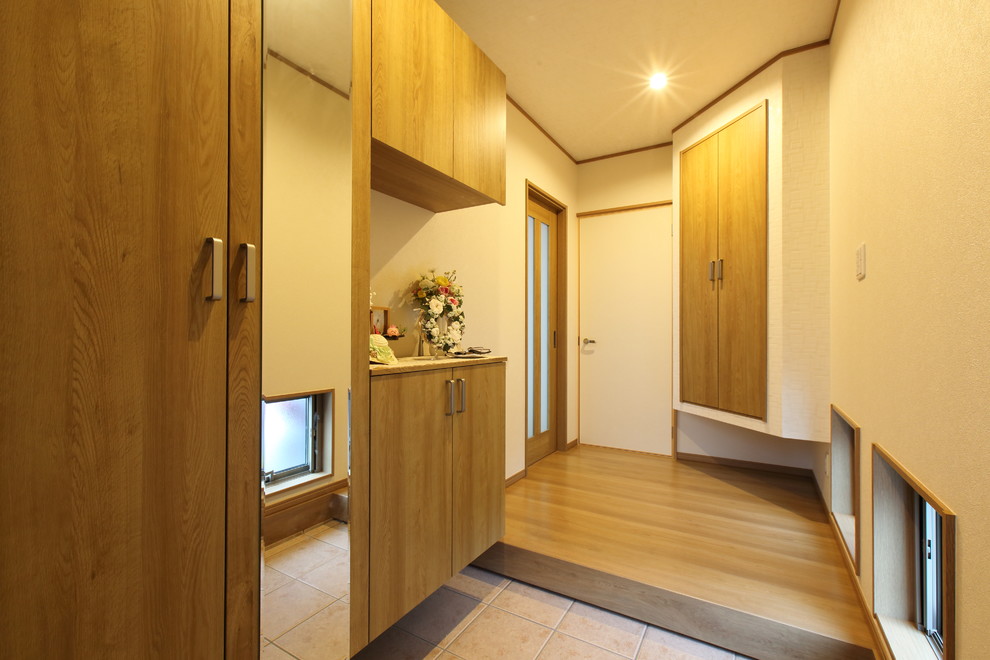 Imagen de hall asiático de tamaño medio con paredes blancas, suelo de contrachapado, puerta de madera en tonos medios y suelo marrón