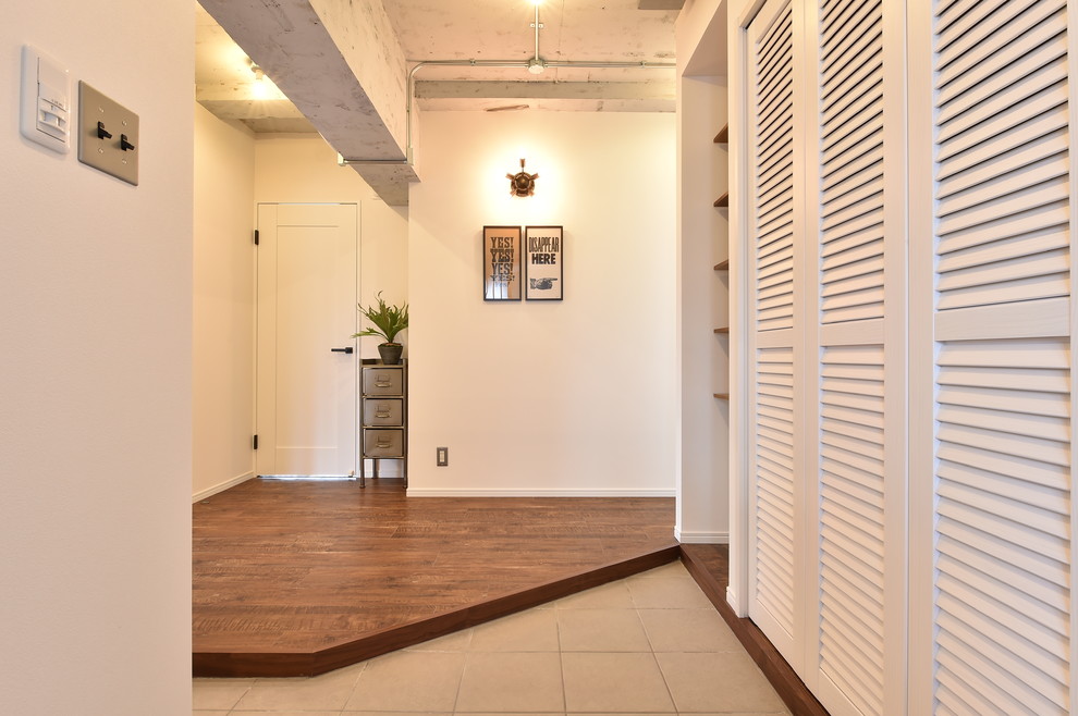 This is an example of an industrial entrance in Other with white walls and beige floors.