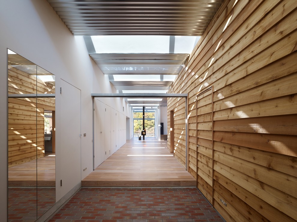 Esempio di un corridoio minimalista con pareti marroni e pavimento in mattoni