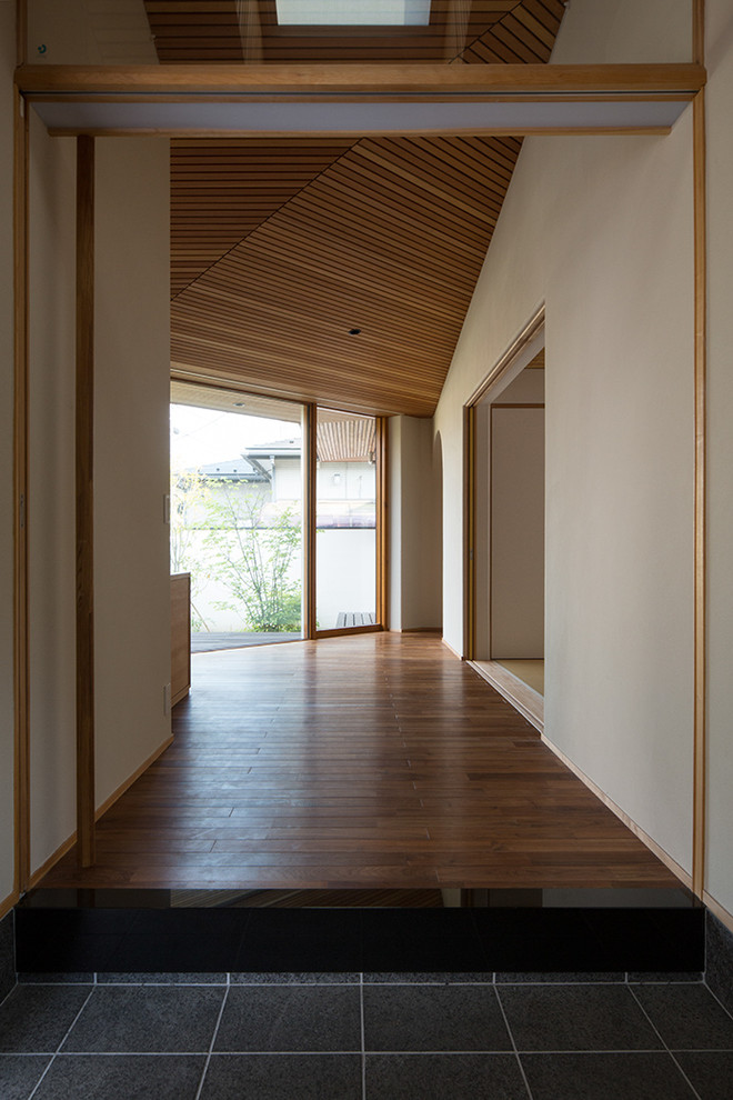 Diseño de puerta principal asiática de tamaño medio con paredes beige, suelo de baldosas de porcelana, puerta simple, puerta de madera en tonos medios y suelo negro