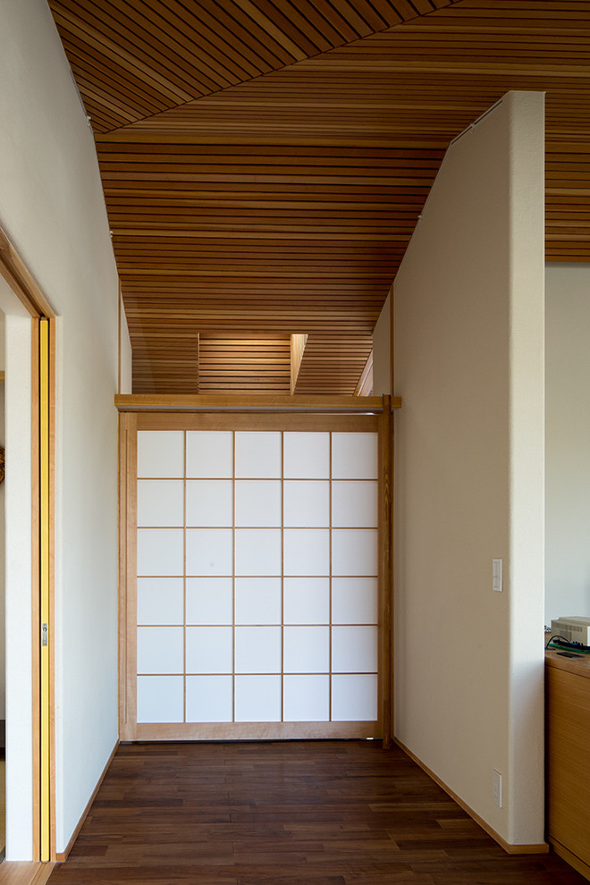 Aménagement d'une porte d'entrée asiatique de taille moyenne avec un mur beige, un sol en carrelage de porcelaine, une porte simple, une porte en bois brun et un sol noir.