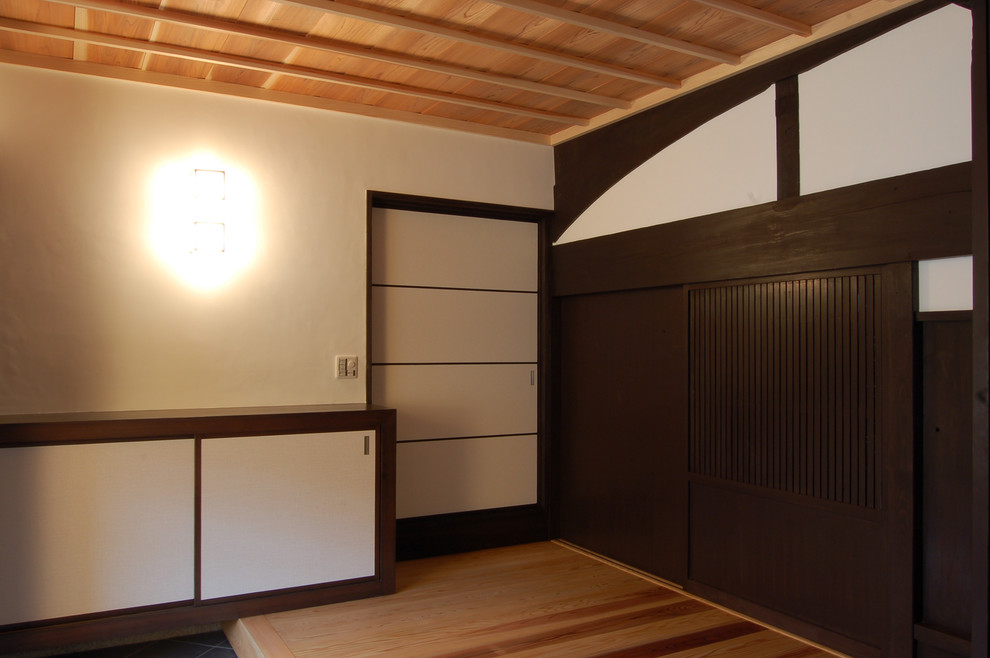 他の地域にあるアジアンスタイルのおしゃれな玄関ホール (白い壁、磁器タイルの床、淡色木目調のドア、グレーの床) の写真