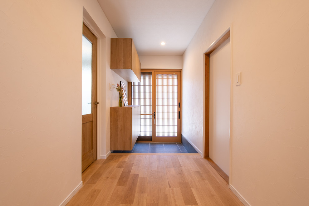 Idee per un piccolo corridoio etnico con pareti bianche, una porta scorrevole, una porta in legno bruno, pavimento grigio, soffitto in carta da parati e carta da parati
