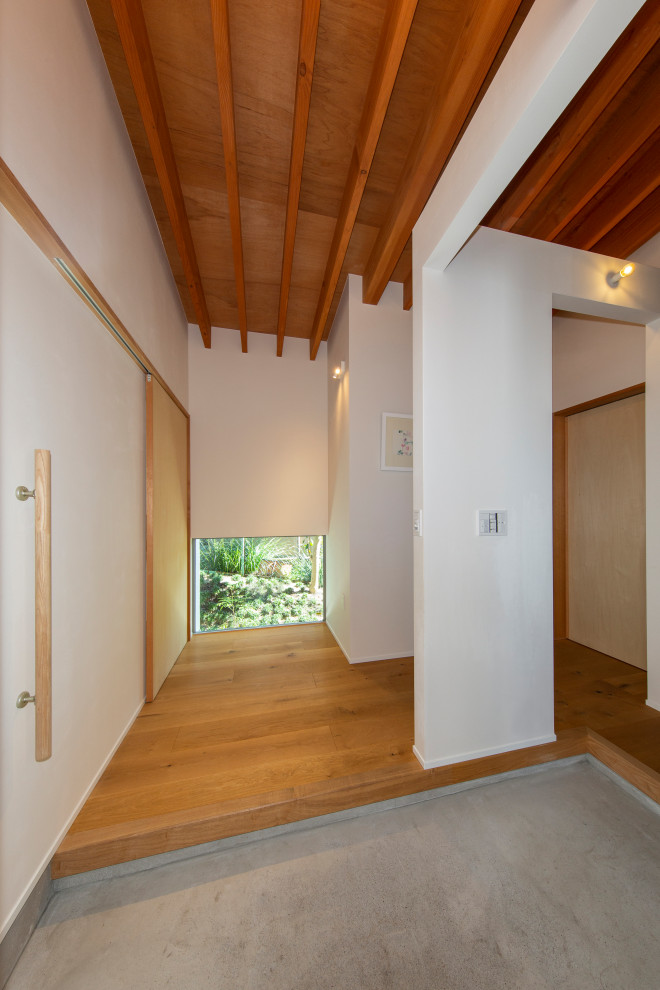 Immagine di un corridoio moderno di medie dimensioni con pareti bianche, pavimento in compensato, una porta singola, una porta in legno bruno e pavimento beige