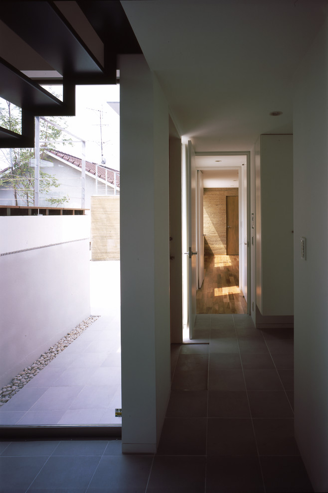 Foto på en stor funkis foajé, med vita väggar, klinkergolv i porslin, en enkeldörr, mellanmörk trädörr och grått golv