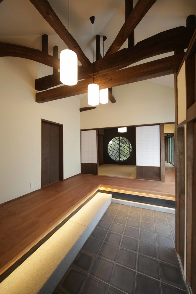 Exempel på en mellanstor hall, med vita väggar, en skjutdörr, en brun dörr och grått golv