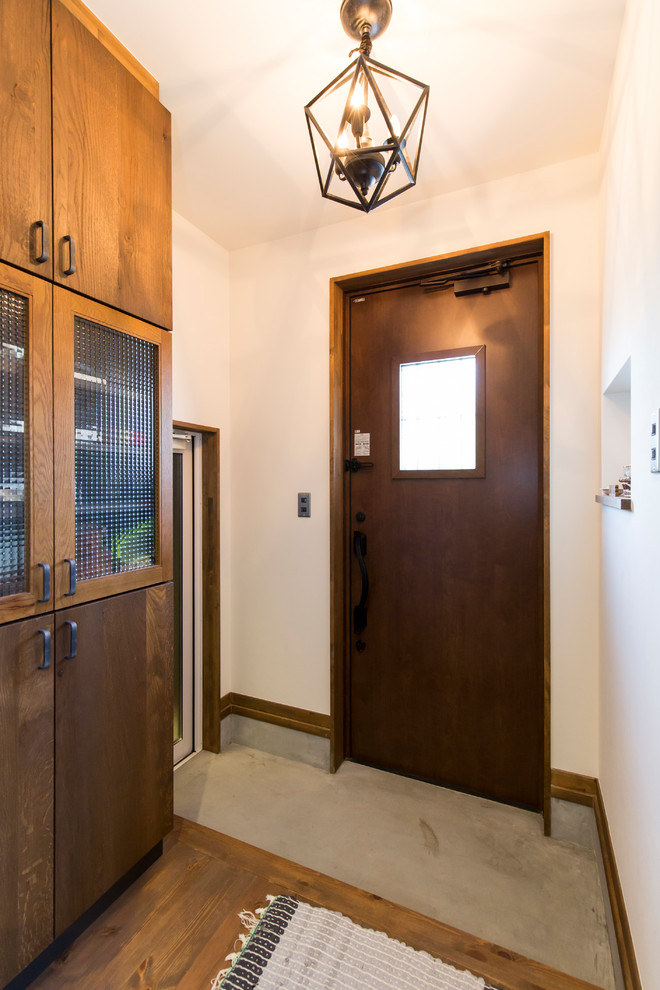 他の地域にある小さなコンテンポラリースタイルのおしゃれな玄関 (白い壁、コンクリートの床、濃色木目調のドア、グレーの床) の写真