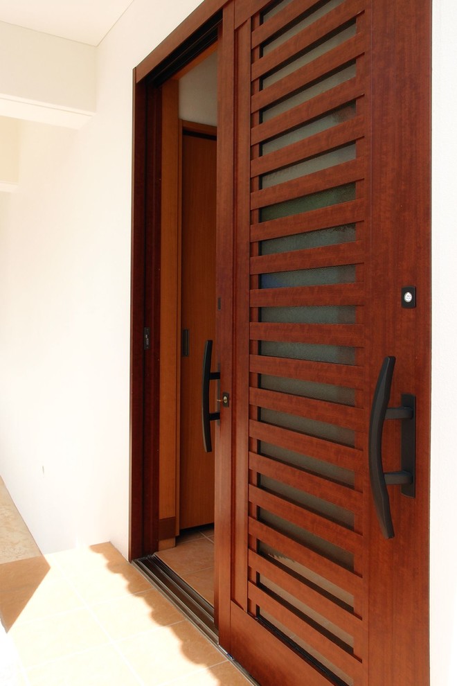 Photo of a mediterranean front door in Other with ceramic flooring, a sliding front door, a brown front door and orange floors.