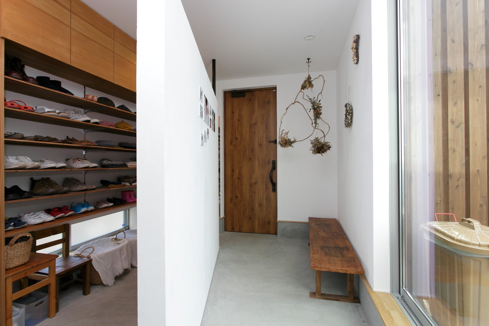 Idéer för en modern entré, med bruna väggar, betonggolv, en enkeldörr, mellanmörk trädörr och grått golv