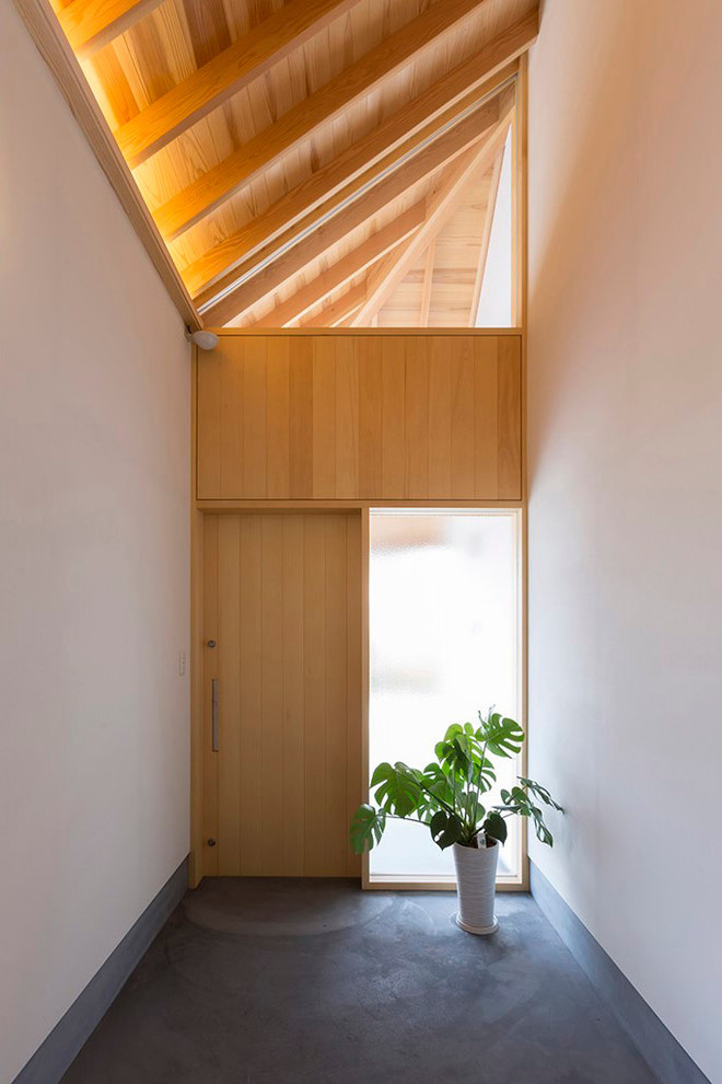 Идея дизайна: узкая прихожая в восточном стиле с белыми стенами, бетонным полом, одностворчатой входной дверью, входной дверью из светлого дерева и серым полом