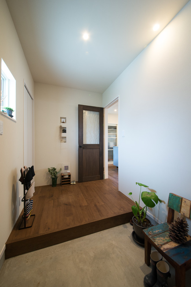 Inspiration pour une entrée chalet avec un mur blanc, une porte simple, une porte en bois brun, sol en béton ciré et un sol gris.