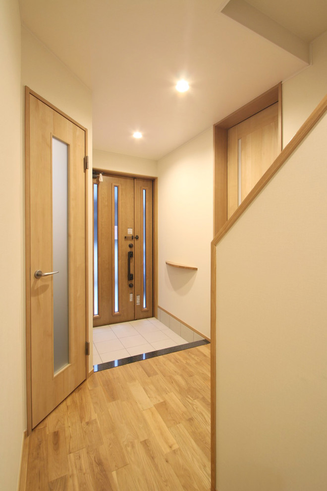 Inspiration for a medium sized hallway with white walls, medium hardwood flooring, a single front door, a medium wood front door and beige floors.