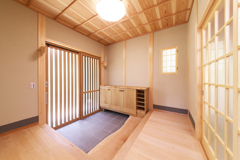 Réalisation d'une entrée asiatique avec un sol en bois brun, une porte en bois brun, un mur beige, une porte coulissante et un plafond en bois.