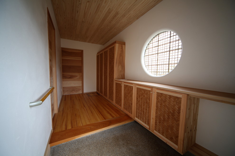 他の地域にある中くらいな和風のおしゃれな玄関ホール (白い壁、茶色いドア、グレーの床) の写真