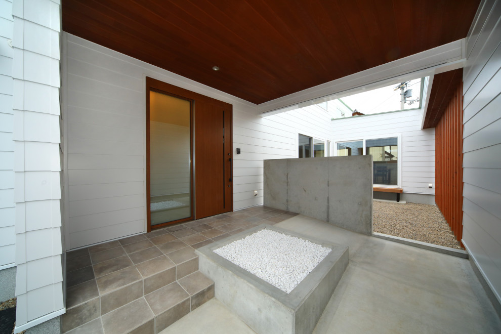 Imagen de distribuidor minimalista con paredes blancas, suelo de granito, puerta corredera, puerta de madera en tonos medios, suelo gris y machihembrado