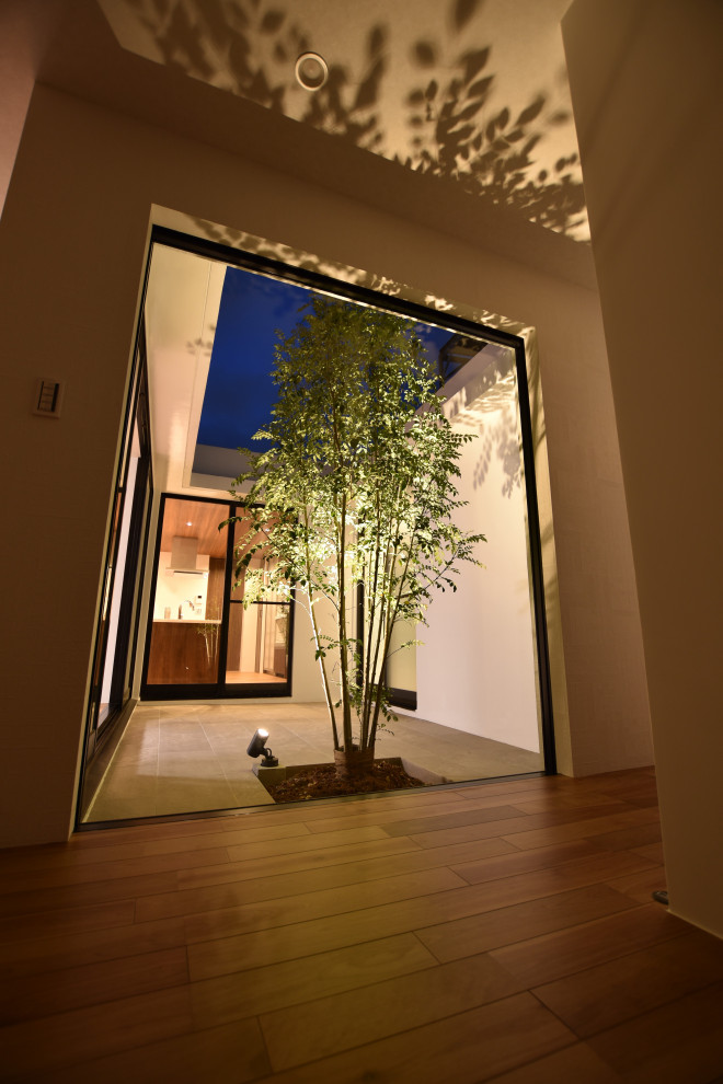 Idée de décoration pour une entrée minimaliste avec un couloir, un mur blanc, un sol en contreplaqué, un sol marron, un plafond en papier peint et du papier peint.