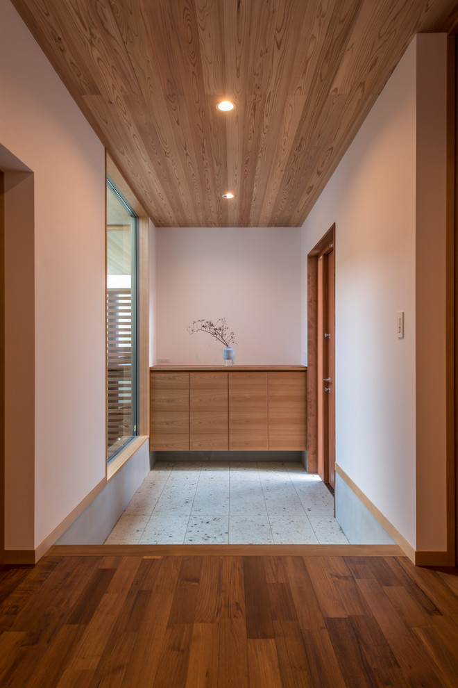 Imagen de hall asiático con paredes blancas, puerta simple, puerta de madera en tonos medios y suelo gris