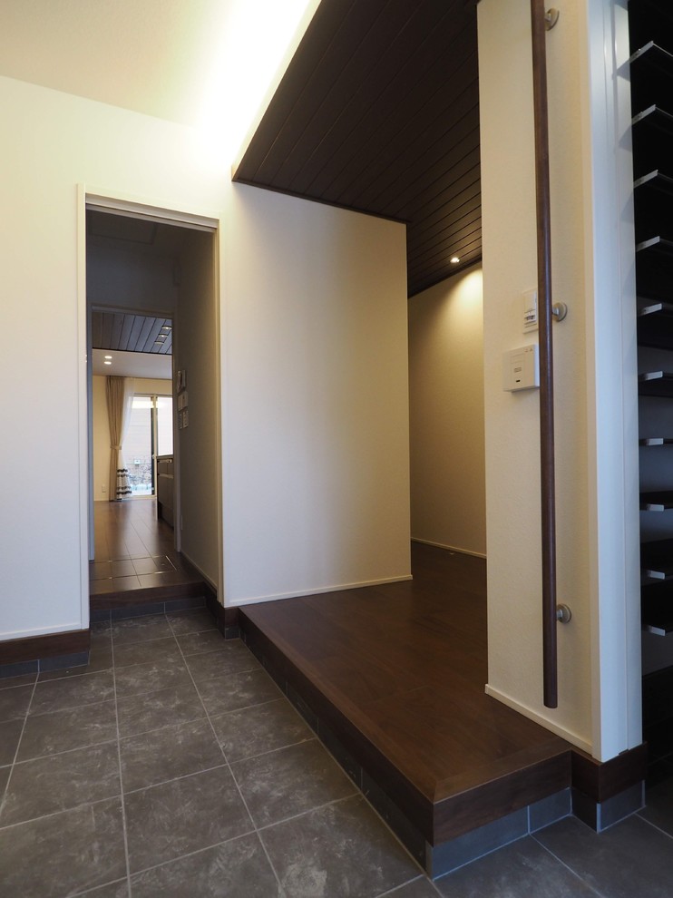 Immagine di un corridoio con pareti bianche, pavimento in legno verniciato, una porta singola, una porta in legno scuro e pavimento marrone