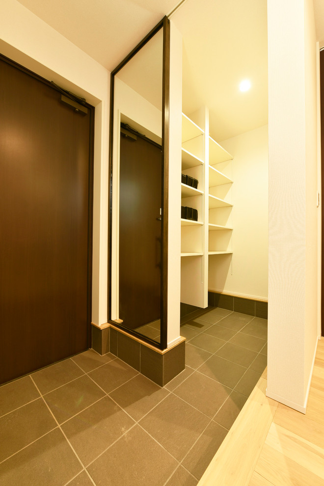 Foto di un corridoio moderno con pareti bianche, pavimento in gres porcellanato, una porta singola, una porta marrone e pavimento nero