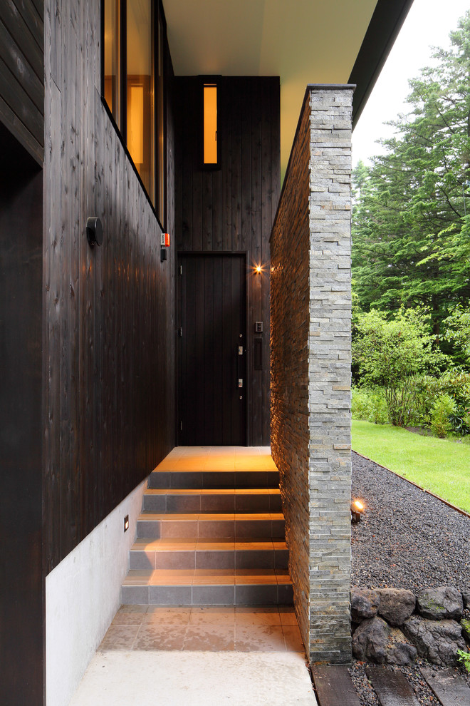 Réalisation d'une porte d'entrée minimaliste de taille moyenne avec un mur noir, un sol en carrelage de céramique, une porte simple, une porte noire et un sol gris.