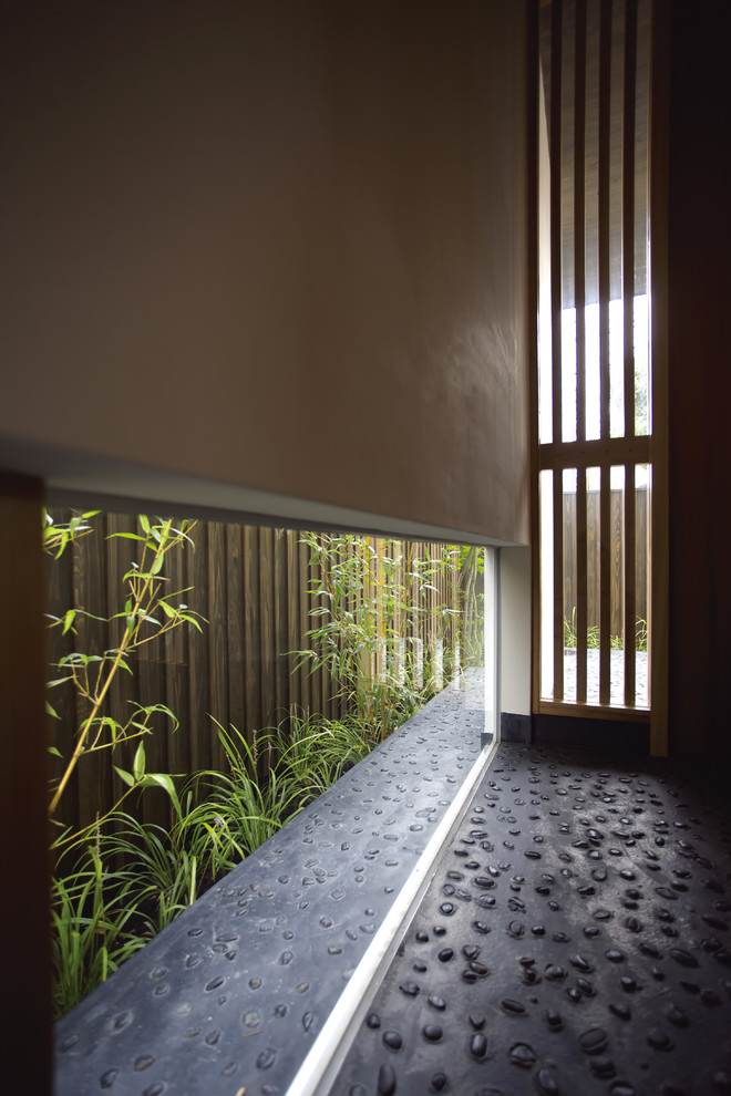 Diseño de hall de estilo zen con paredes blancas, suelo de cemento, puerta simple y puerta de madera oscura